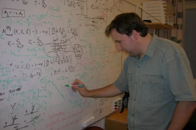 A man writing on a whiteboard. Photo.