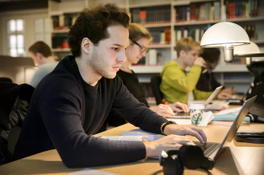 Three people with laptops in a library. Photo: Johan Bävman.