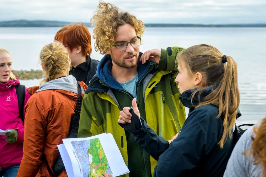 Students standing close to a lake, with maps in their hands. Photo: Kennet Ruona.